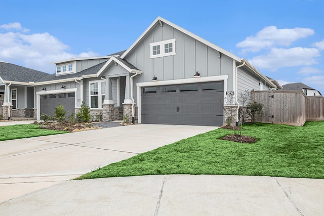 view of front of house featuring driveway, stone siding, fence, a front lawn, and board and batten siding