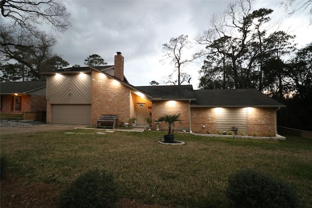 view of front of home featuring driveway, brick siding, a chimney, and a front yard