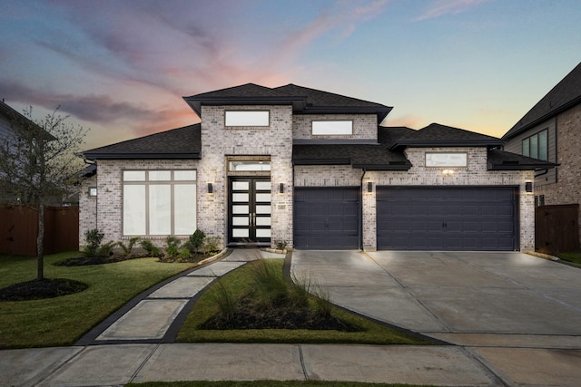 prairie-style home with an attached garage, driveway, brick siding, and a shingled roof