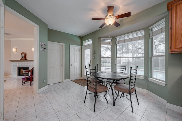 tiled dining area with ceiling fan, a tile fireplace, and a wealth of natural light