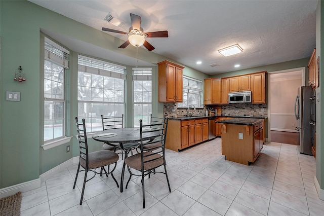 kitchen with sink, backsplash, light tile patterned flooring, a center island, and stainless steel appliances