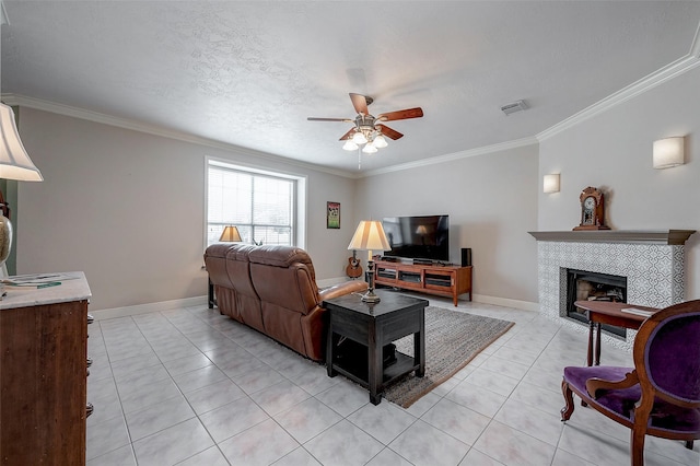 tiled living room featuring a textured ceiling, a tiled fireplace, crown molding, and ceiling fan