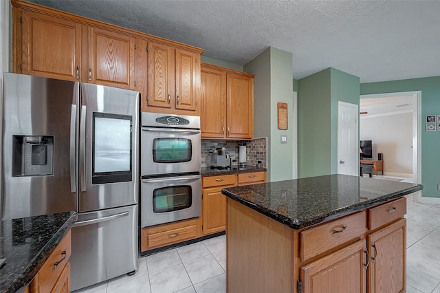 kitchen featuring light tile patterned flooring, appliances with stainless steel finishes, a kitchen island, and decorative backsplash