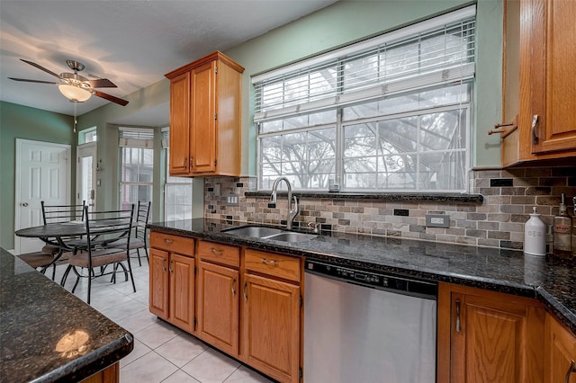 kitchen featuring dishwasher, dark stone counters, backsplash, light tile patterned floors, and sink