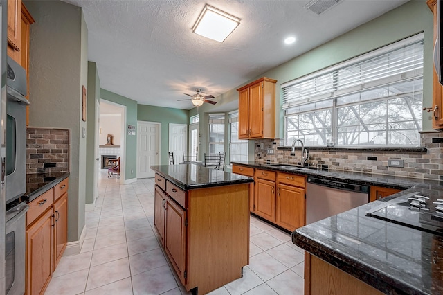 kitchen with light tile patterned floors, sink, backsplash, a kitchen island, and stainless steel appliances