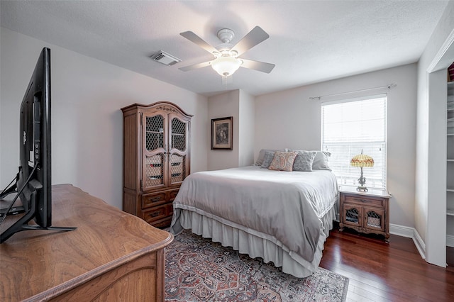 bedroom with a textured ceiling, dark wood-type flooring, and ceiling fan