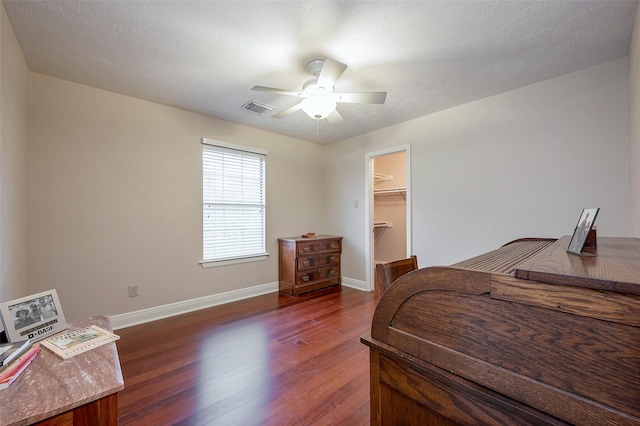 bedroom featuring a closet, ceiling fan, a textured ceiling, a spacious closet, and dark hardwood / wood-style floors