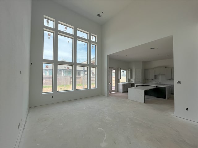 4410 Southpoint Way S, Fulshear, TX 77441 - unfurnished living room with unfinished concrete floors, plenty of natural light, and a high ceiling
