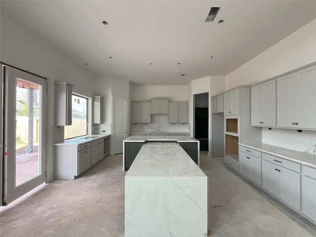 4410 Southpoint Way S, Fulshear, TX 77441 - kitchen featuring gray cabinetry, concrete floors, backsplash, and a kitchen island