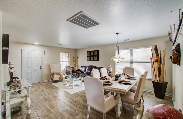 dining room featuring light hardwood / wood-style flooring and a textured ceiling