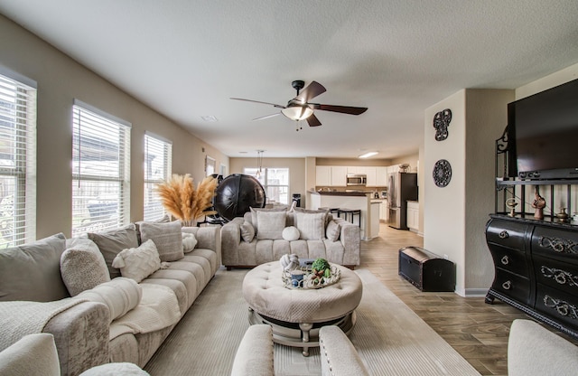 living room with light wood-type flooring, a textured ceiling, and ceiling fan