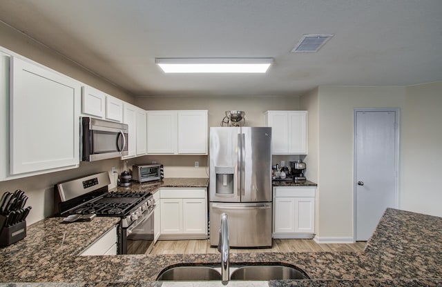 kitchen featuring sink, dark stone countertops, white cabinets, and stainless steel appliances