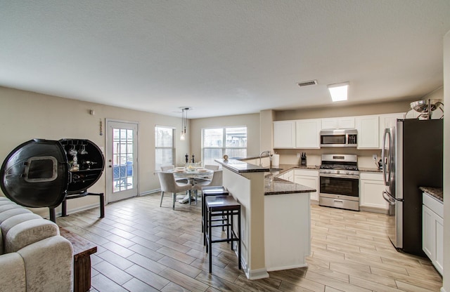 kitchen with hanging light fixtures, white cabinetry, stainless steel appliances, and a kitchen breakfast bar