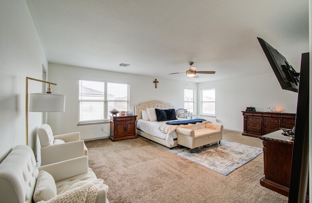 bedroom with light carpet, ceiling fan, and a textured ceiling