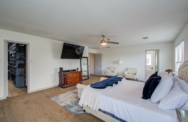 carpeted bedroom featuring ceiling fan and a walk in closet