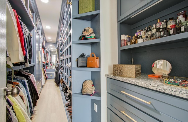 walk in closet with light hardwood / wood-style floors