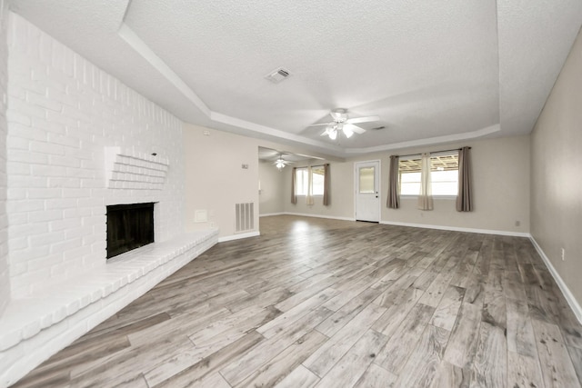 unfurnished living room with a fireplace, light hardwood / wood-style flooring, and a raised ceiling