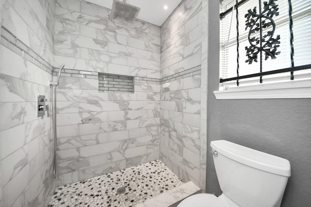 bathroom featuring tiled shower and toilet