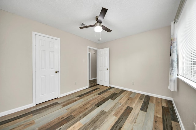 unfurnished bedroom with hardwood / wood-style flooring, ceiling fan, and a textured ceiling