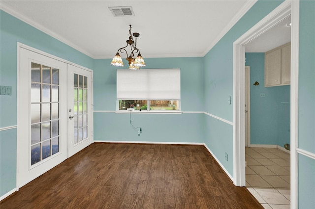 unfurnished dining area featuring a notable chandelier, french doors, dark hardwood / wood-style flooring, and ornamental molding