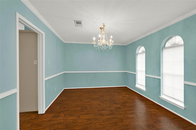 empty room featuring a chandelier, crown molding, dark hardwood / wood-style floors, and a textured ceiling