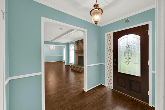 foyer entrance with ornamental molding, dark wood-type flooring, and a fireplace