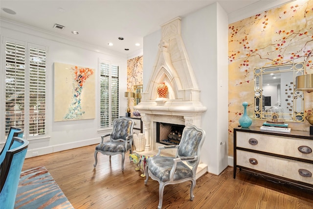 living area with a fireplace, crown molding, and wood-type flooring