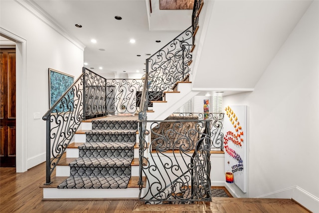 stairs with crown molding and hardwood / wood-style floors