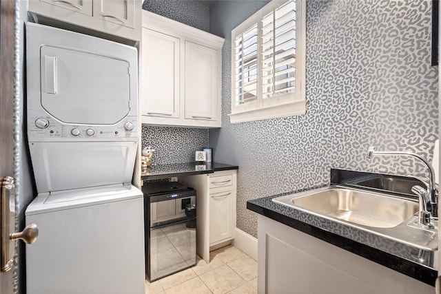 laundry room with sink, cabinets, stacked washer and clothes dryer, and light tile patterned floors