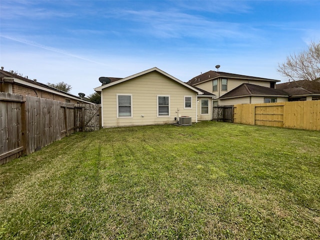 rear view of property with central AC and a yard