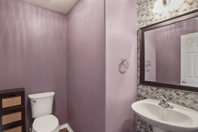 bathroom with toilet, backsplash, and a sink