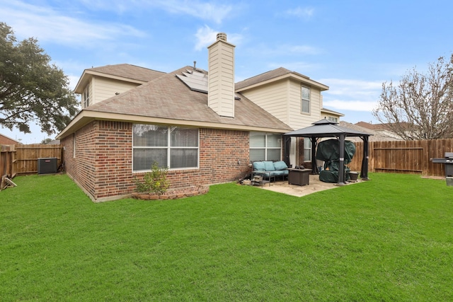 back of property with brick siding, a fenced backyard, a yard, and a gazebo