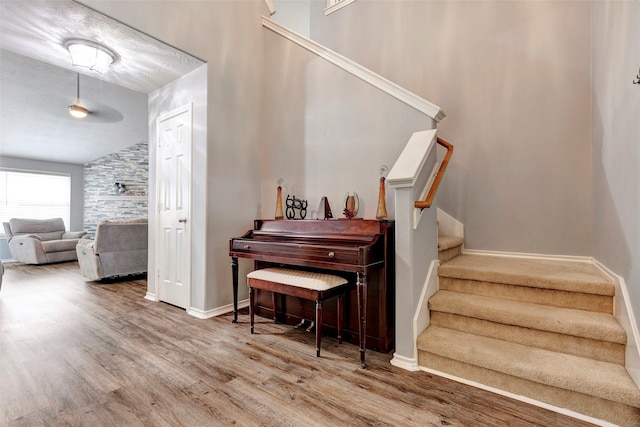 staircase featuring vaulted ceiling, wood-type flooring, and a fireplace