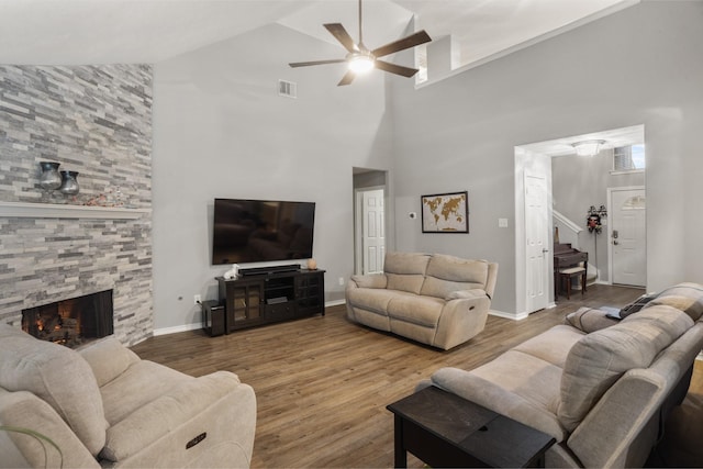 living room with ceiling fan, a fireplace, wood finished floors, visible vents, and baseboards