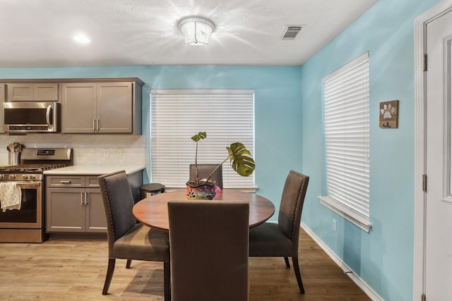 dining area featuring light wood-style floors, baseboards, and visible vents