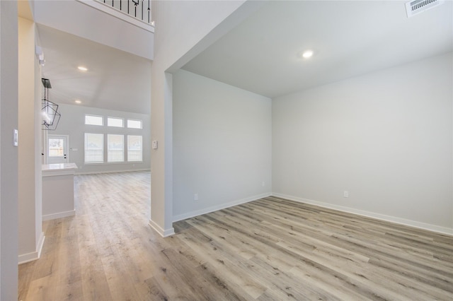 spare room featuring light hardwood / wood-style floors, a chandelier, and a high ceiling