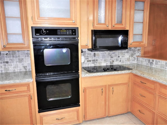 kitchen with light tile patterned floors, black appliances, light stone counters, and tasteful backsplash