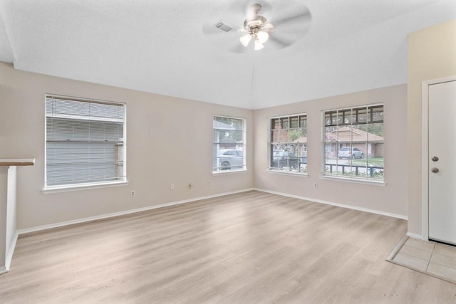 spare room with plenty of natural light, ceiling fan, vaulted ceiling, and light hardwood / wood-style flooring