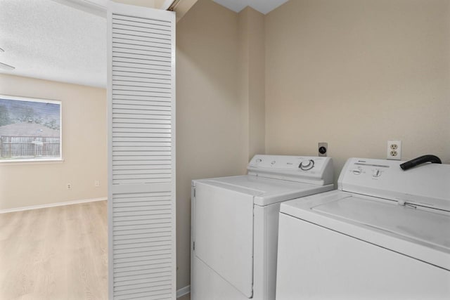 laundry area with washing machine and clothes dryer and light hardwood / wood-style floors