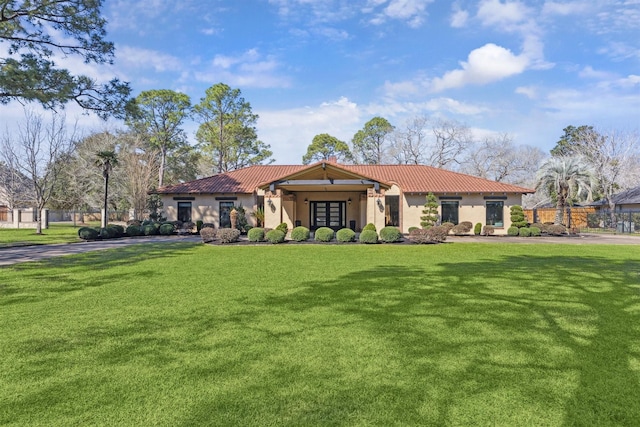 mediterranean / spanish house with a tiled roof, a front lawn, and stucco siding