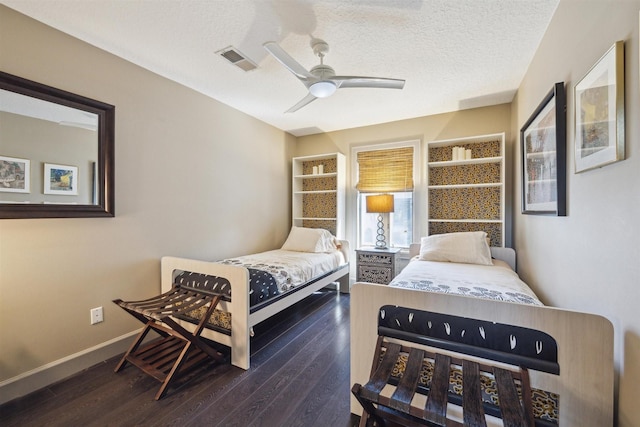 bedroom with dark wood-type flooring, visible vents, a textured ceiling, and baseboards