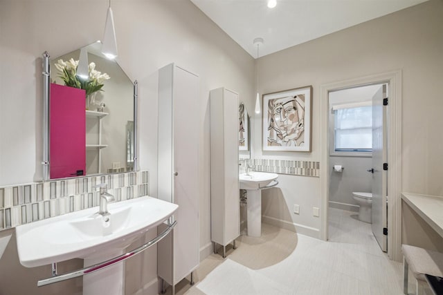 bathroom with two sinks, toilet, and baseboards