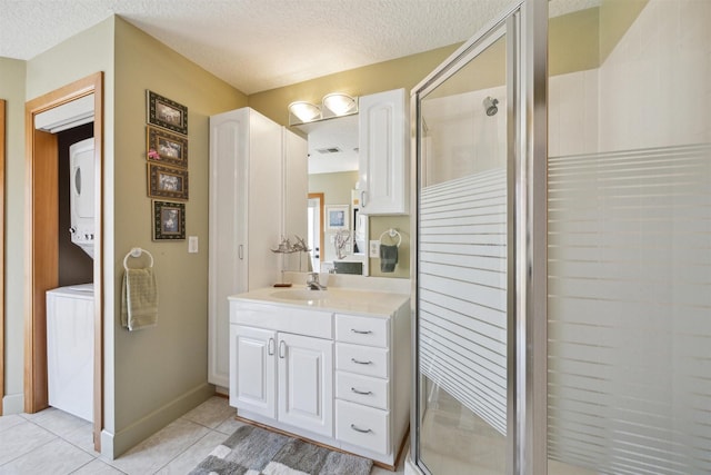 full bathroom with stacked washer / dryer, a textured ceiling, vanity, a shower stall, and tile patterned floors