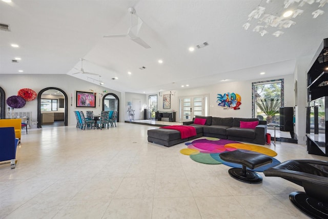 living area featuring lofted ceiling, plenty of natural light, ceiling fan, and visible vents