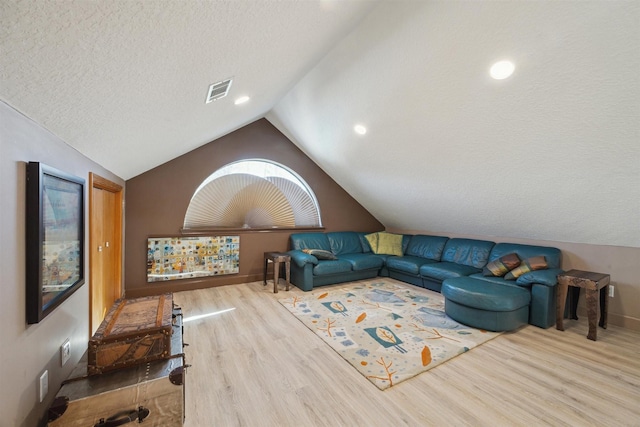 living room with lofted ceiling, a textured ceiling, baseboards, and wood finished floors