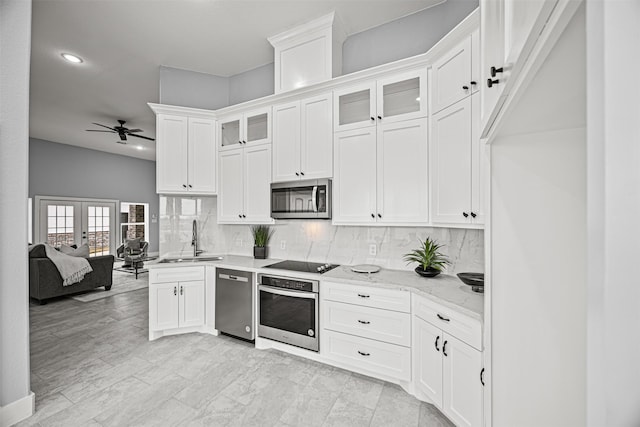 kitchen with appliances with stainless steel finishes, white cabinetry, light stone counters, and sink