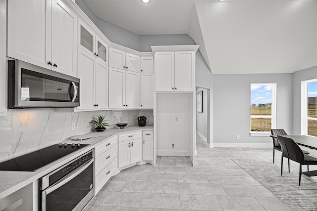 kitchen with tasteful backsplash, stainless steel appliances, white cabinets, and light stone counters