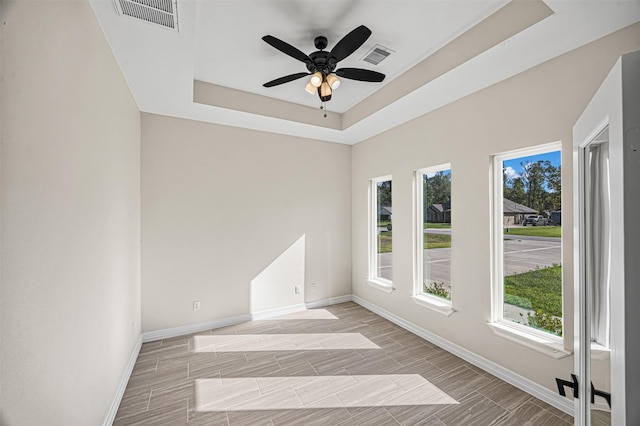 spare room with ceiling fan and a tray ceiling