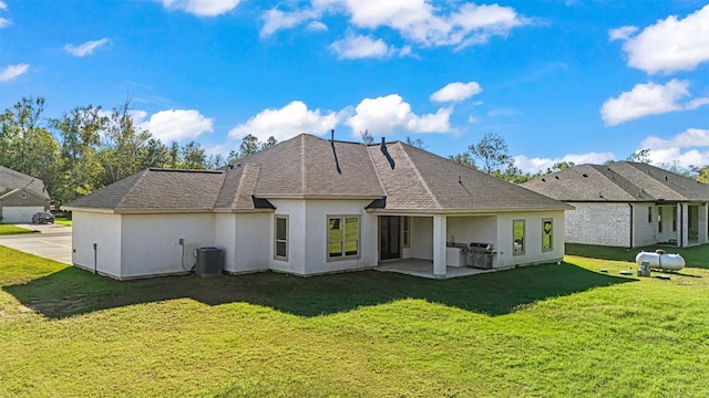 rear view of house with a yard, a patio, central AC unit, and area for grilling