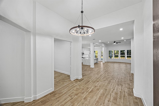 interior space featuring light wood-type flooring, ceiling fan with notable chandelier, baseboards, and recessed lighting